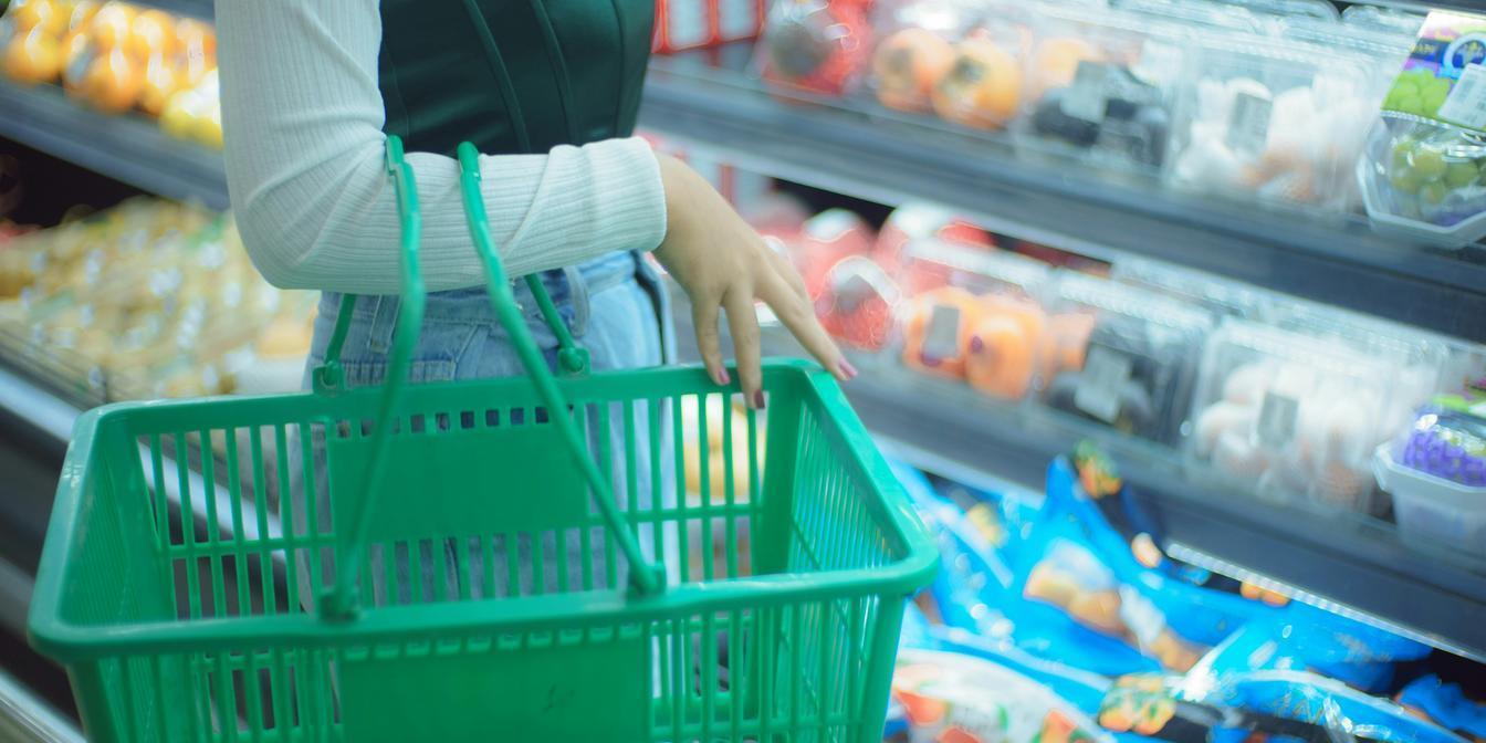 A shopper checking ingredients, allergens, origin and pack size on a grocery product